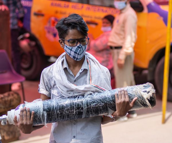 Symbolbild: Niedergeschlagener junger Mann mit leerer Sauerstoffflasche, Indien steht vor einem Engpass an medizinischem Sauerstoff