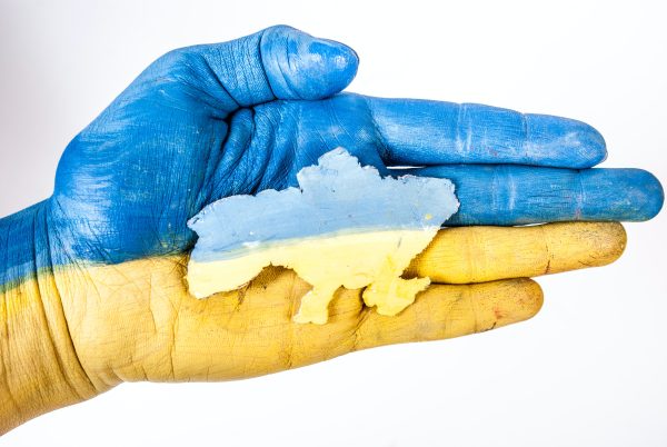 Hand in den Farben der ukrainischen Flagge hält eine Miniatur der Ukraine, Foto Credits: Elena Mozhvilo, unsplash.com